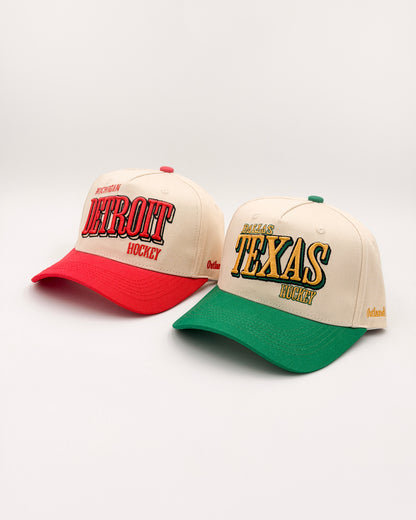 Outland Club Co. City Ice Collection - Detroit (red brim) and Dallas Texas (green brim) Classic Snapback Hats side by side, cream crowns with hockey embroidery